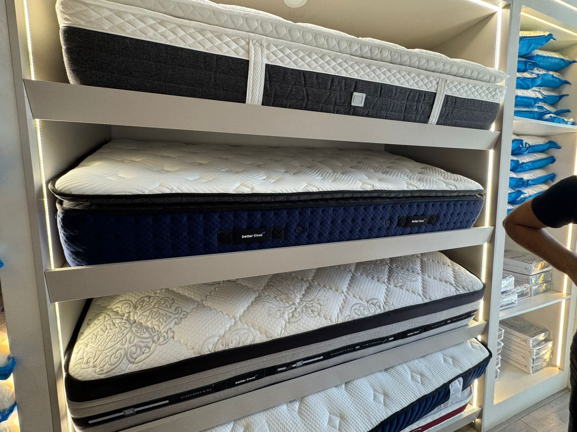 Matelas finis rangés sur des étagères éclairées, garnitures et matériaux stockés à proximité