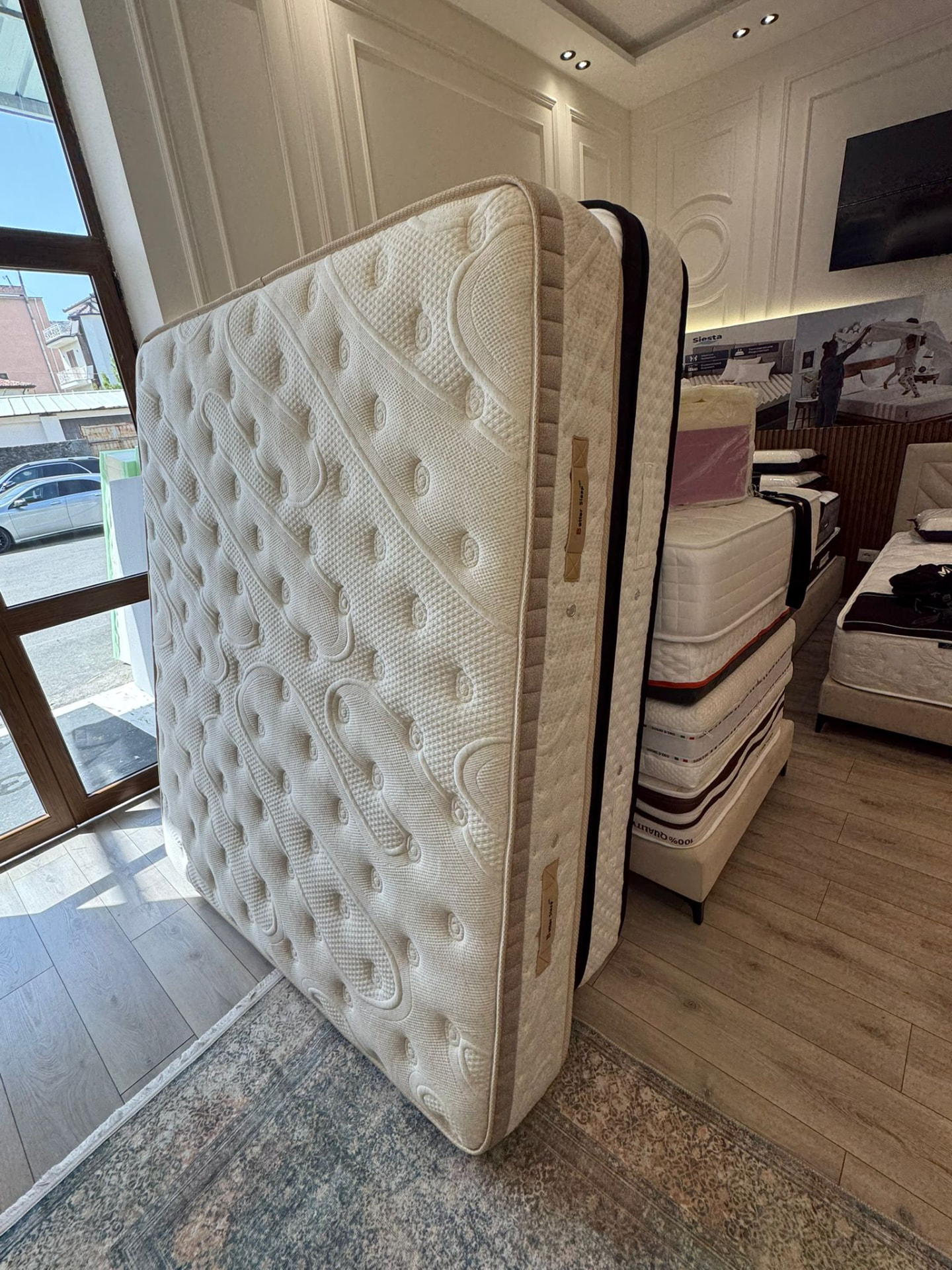 Matelas ivoire matelassé présenté debout dans notre showroom, coutil et finitions visibles